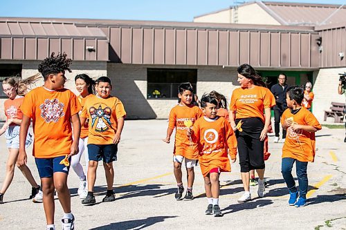 MIKAELA MACKENZIE / FREE PRESS
	
Teacher-librarian Suzanne Beauregard leads students out to place orange hearts along the walkway at cole Van Walleghem School Thursday, Sept. 26, 2024. Beauregard helped put together the orange heart walkway project at the school.

For Maggie story.
Winnipeg Free Press 2024