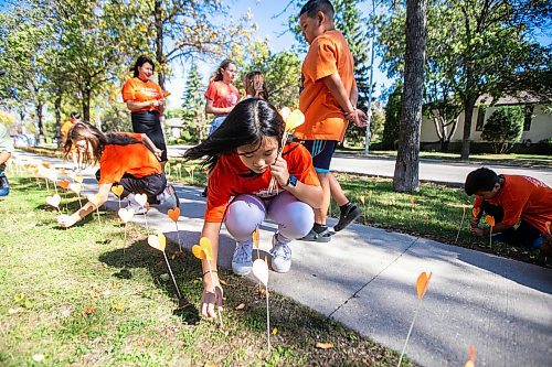 MIKAELA MACKENZIE / FREE PRESS
	
Grade eight student Kyandra places orange hearts along the walkway project at cole Van Walleghem School Thursday, Sept. 26, 2024. 

For Maggie story.
Winnipeg Free Press 2024