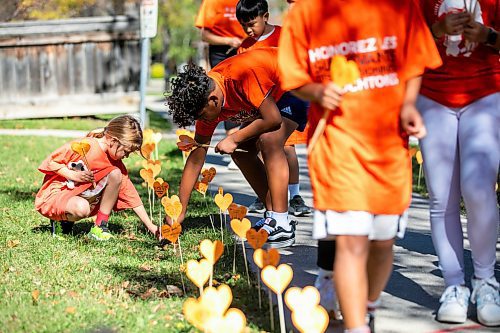 MIKAELA MACKENZIE / FREE PRESS
	
Students Ivy (left, grade two) and Xavier (right, grade seven) place orange hearts along the walkway project at cole Van Walleghem School Thursday, Sept. 26, 2024. 

For Maggie story.
Winnipeg Free Press 2024