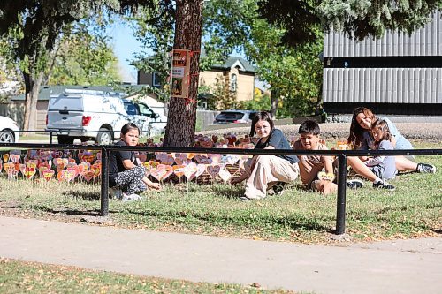 Betty Gibson School students hold heart symbols to honour students who never made it home from residential schools. The students made paintings on paper in heart shapes with texts like 'Be Strong', glued each to sticks and tucked in the ground under a tree in front of the school.  (Abiola Odutola/The Brandon Sun)