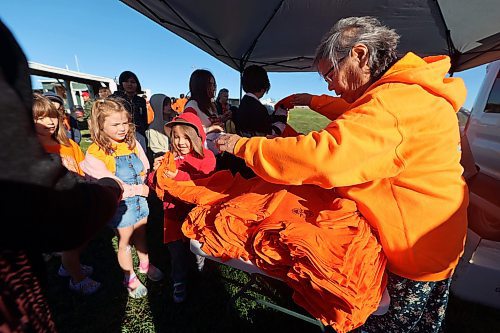 Norma McKay hands out shirts to children from the Rolling River School Division during Truth and Reconciliation Day events at the Rolling River First Nation on Friday. (Connor McDowell/Brandon Sun)