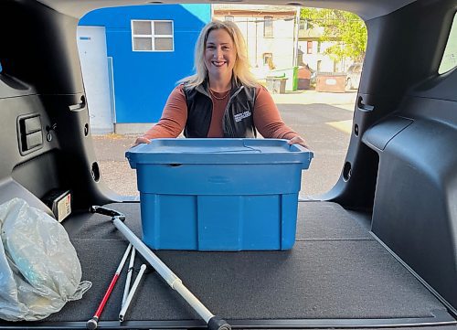 Niki Harper with Vision Loss Rehabilitation Canada, a sister organization to CNIB, loads a bin into the back of a 2024 black Chevrolet Equinox that was purchased by the Wheat City Lions Club and donated to the two non-profits. (Michele McDougall/The Brandon Sun) 