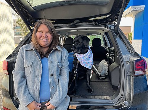 Andrea McIvor and her guide dog, Hilda, a seven-year-old Labrador retriever, sit on the rear bumper of a 2024 black Chevrolet Equinox that was purchased by the Wheat City Lions Club and donated to the CNIB and its sister organization, Vision Loss Rehabilitation Canada. (Michele McDougall/The Brandon Sun) 
