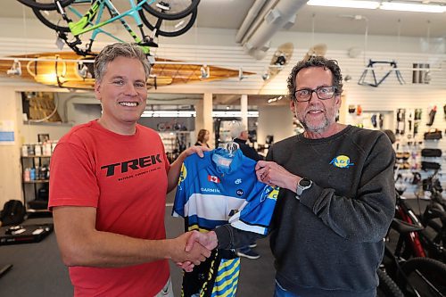 Brandon cyclist Grant Hamilton (left) is presented with a jersey by A&L Cycle co-owner Cam Wirch at the A&L Cycle office on Rosser Avenue in Brandon on Wednesday afternoon. The bike shop is sponsoring Hamilton in next year's Tour 21, a charity ride affiliated with the famed cycling event Tour de France. (Abiola Odutola/The Brandon Sun) 