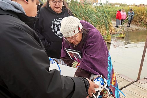 Julia Brandon, who lives in Brandon and is originally from Waywayseecappo First Nation, takes flower petals and tobacco to place in the Assiniboine River in memory of her sister Victoria Brandon, who was severely beaten at age 19 and left permanently severely disabled, during the Sisters In Spirit petal ceremony at Dinsdale Park on Friday morning. Victoria Brandon ultimately passed away in 2016. (Tim Smith/The Brandon Sun)