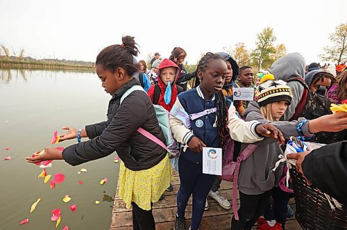 Students from École New Era School take flower petals to place in the Assiniboine River in honour and remembrance of missing and murdered indigenous women and girls during Friday's ceremony. (Tim Smith/The Brandon Sun)