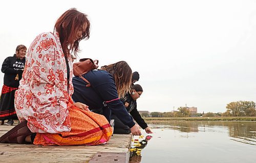 Women place flower petals and tobacco in the Assiniboine River in honour and remembrance of missing and murdered indigenous women and girls during the Sisters In Spirit petal ceremony at Dinsdale Park on Friday morning. (Tim Smith/The Brandon Sun)