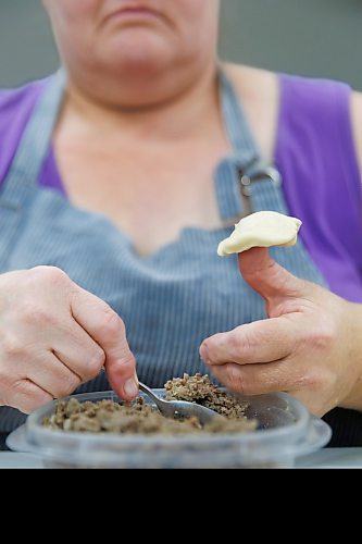 MIKE DEAL / FREE PRESS
Deb takes little balls of dough and adds the filing.
Deb Rogalsky, founder of Deb's Meat Buns, runs her home-based enterprise out of a commercial kitchen attached to her home in Landmark, Manitoba. 
She bakes as many as 300 dozen meat buns a week.
She turns out over a dozen varieties of meat buns, or perishky, including pulled pork, buffalo chicken and taco - as well as one called the Original (ground beef, onions, mashed potatoes) based on a recipe developed by Deb's mom, decades ago. 
Reporter: Dave Sanderson
241009 - Wednesday, October 09, 2024.