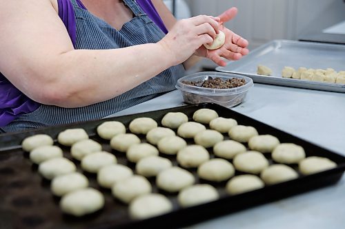 MIKE DEAL / FREE PRESS
Deb takes little balls of dough and adds the filing.
Deb Rogalsky, founder of Deb's Meat Buns, runs her home-based enterprise out of a commercial kitchen attached to her home in Landmark, Manitoba. 
She bakes as many as 300 dozen meat buns a week.
She turns out over a dozen varieties of meat buns, or perishky, including pulled pork, buffalo chicken and taco - as well as one called the Original (ground beef, onions, mashed potatoes) based on a recipe developed by Deb's mom, decades ago. 
Reporter: Dave Sanderson
241009 - Wednesday, October 09, 2024.