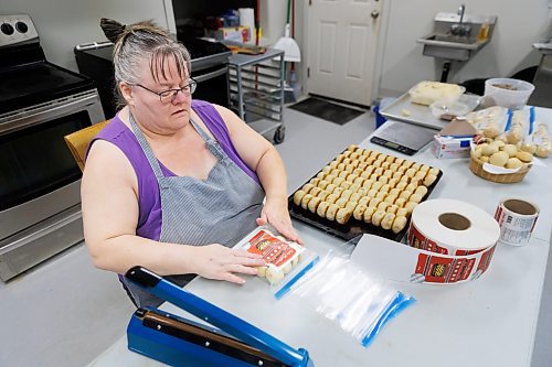 MIKE DEAL / FREE PRESS
A label is applied to a package.
Deb Rogalsky, founder of Deb's Meat Buns, runs her home-based enterprise out of a commercial kitchen attached to her home in Landmark, Manitoba. 
She bakes as many as 300 dozen meat buns a week.
She turns out over a dozen varieties of meat buns, or perishky, including pulled pork, buffalo chicken and taco - as well as one called the Original (ground beef, onions, mashed potatoes) based on a recipe developed by Deb's mom, decades ago. 
Reporter: Dave Sanderson
241009 - Wednesday, October 09, 2024.