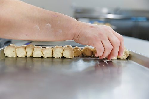 MIKE DEAL / FREE PRESS
Deb fills a tray with little balls of dough that she weighs individually. As he children grew up, they often dreamed of this part of the process being automated.
Deb Rogalsky, founder of Deb's Meat Buns, runs her home-based enterprise out of a commercial kitchen attached to her home in Landmark, Manitoba. 
She bakes as many as 300 dozen meat buns a week.
She turns out over a dozen varieties of meat buns, or perishky, including pulled pork, buffalo chicken and taco - as well as one called the Original (ground beef, onions, mashed potatoes) based on a recipe developed by Deb's mom, decades ago. 
Reporter: Dave Sanderson
241009 - Wednesday, October 09, 2024.