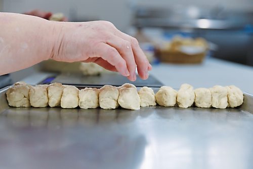 MIKE DEAL / FREE PRESS
Deb fills a tray with little balls of dough that she weighs individually. As he children grew up, they often dreamed of this part of the process being automated.
Deb Rogalsky, founder of Deb's Meat Buns, runs her home-based enterprise out of a commercial kitchen attached to her home in Landmark, Manitoba. 
She bakes as many as 300 dozen meat buns a week.
She turns out over a dozen varieties of meat buns, or perishky, including pulled pork, buffalo chicken and taco - as well as one called the Original (ground beef, onions, mashed potatoes) based on a recipe developed by Deb's mom, decades ago. 
Reporter: Dave Sanderson
241009 - Wednesday, October 09, 2024.