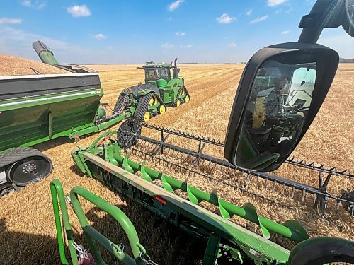 Reflected in the rear-view mirror, Neil Waldner of the Hillside Hutterite Colony watches closes as his load of wheat is unloaded on an 80-acre field north of Brandon on Wednesday afternoon. (Matt Goerzen/The Brandon Sun)