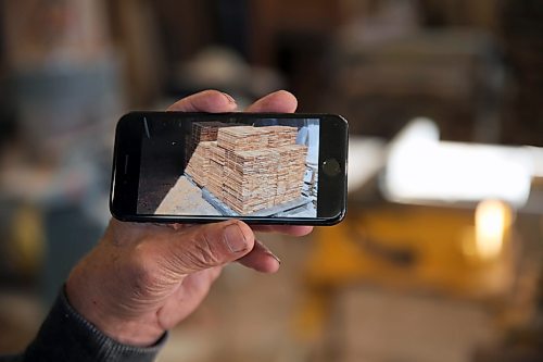 Neil Friesen holds a photo of two pallets of wood shingles. He cut the shingles from old hydro poles, which he buys at about $250 for a semi truck load full. (Connor McDowell/Brandon Sun)