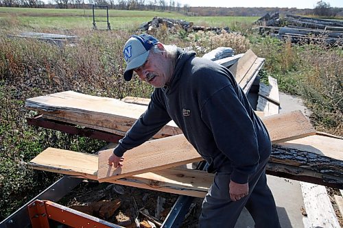 Neil Frieson demonstrates a step in converting old hydro poles into wooden shingles for rooftops. He is seen with a wooden board cut from a hydro pole on his property near Wawanesa. (Connor McDowell/Brandon Sun)