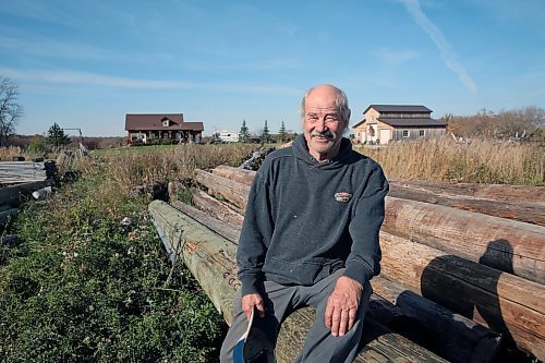 Neil Frieson sits on a pile of old hydro poles, stacked in his yard. The Wawanesa resident buys them by the semi truck full, and then uses them for woodworking projects. (Connor McDowell/Brandon Sun)