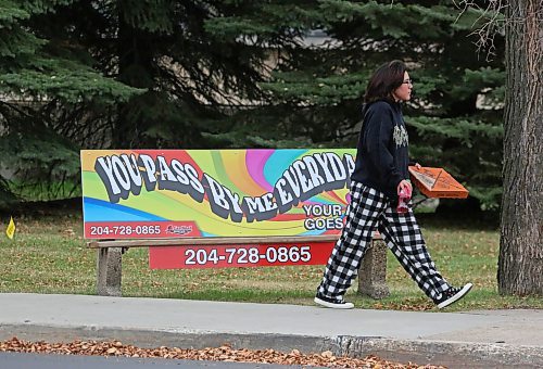 A woman walks past a bench sign on 18th Street in front of Brandon University on Friday afternoon. (Matt Goerzen/The Brandon Sun)