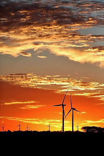 The rising sun silhouettes a pair of wind turbines against a glowing red sky at St. Joseph, MB in this file image from 2022. (Matt Goerzen/The Brandon Sun)