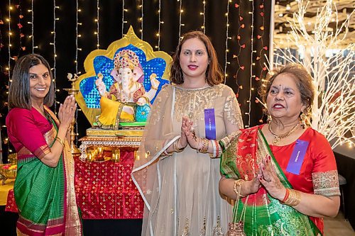 BROOK JONES/FREE PRESS
The Hindu Society of Manitoba hosts its annual Diwali Mela (Festival of Lights) at the RBC Convention Centre in Winnipeg, Man. Saturday, Oct. 19, 2024. Romona Goomansingh (middle) who is wearing a piece of Indian clothing called a anarkali salwar kameez, Bhawna Thakrar (left) who is draped in a traditional sari and Romona's mother, Mona Goomansingh (right), who is weaing a gujarati are pictured praying in front of Lord Ganesha.