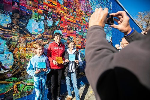 MIKAELA MACKENZIE / FREE PRESS
	
Allie Reinhardt (nine, left), Brenda Krueger, and Kaia Tan (11) take a photo with their painted tiles at the Canada Connects Love &amp; Family mosaic mural unveiling at 1797 Portage Avenue on Monday, Oct. 21, 2024.

For biz story.
Winnipeg Free Press 2024