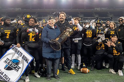 BROOK JONES / WINNIPEG FREE PRESS
The Dakota Collegiate Lancers earned a 28-7 victory over the Grand Park High School Pirates in the Winnipeg High School Football League AAAA Final of the ANAVETS Bowl at IG Field in Winnipeg, Man., Friday, Nov. 10, 2023. Pictured: Rosie Towers, who is the sports convenor at the ANAVETS Rockwood Unit No. 303, smiles while holding the ANAVETS Bowl as she stands with Dakota Lancers head coach Mitchell Harrison and his players during the team's celebration.