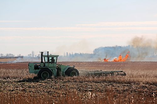 A farmer cultivates his field outside of Souris on Saturday afternoon while a stubble fire burns in the background. (Connor McDowell/The Brandon Sun)