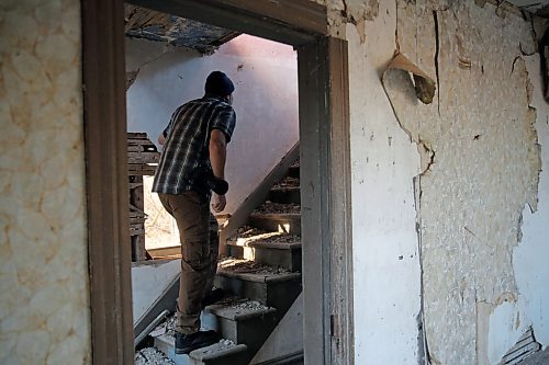 Albert Roy creeps up a rubble-covered staircase. Feeling brave with the company of others, he took a risk of walking up the stairs that were likely built in the late 1800s. The floor beneath the stairs was littered with holes. (Connor McDowell/Brandon Sun)