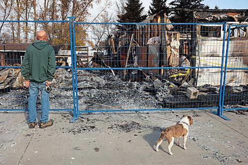 Lawrence Medd and his french bulldog Lola walk Thursday past the duplex his father Bill Medd lived in until it was destroyed by a fire on Oct. 20. (Tim Smith/The Brandon Sun)