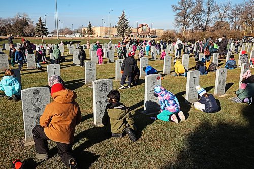 Students place poppies at the base of military gravestones during the annual No Stone Left Alone event at the Brandon Cemetery on Tuesday morning. Hundreds, including students from multiple Brandon schools, took part in the event meant to honour the sacrifice and service of soldiers in Canada's military. (Photos by Tim Smith/The Brandon Sun)