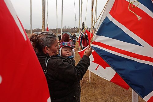 11112024
Roxanna Gott and her eight-month-old son Douglas Pratt help fellow community members take down the flags that fly at the war memorial at Sioux Valley Dakota Nation&#x2019;s Pow Wow grounds following the Remembrance Day service at the SVDN Community Centre on Monday. The flags are raised for the weekend of Sioux Valley&#x2019;s Pow Wow and then raised again on National Indigenous Veterans Day (November 8) and removed on Remembrance Day. 
(Tim Smith/The Brandon Sun)