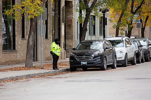 BROOK JONES / WINNIPEG FREE PRESS
The Winnipeg Parking Authority is a speicla operating agency of hte City of Winnipeg. Pictured: A parking compliance offer with the Winnipeg Parking Authority stands next to parked vehicle along Market Ave., in Winnipeg, Man., Wednesday, Oct. 5, 2023.