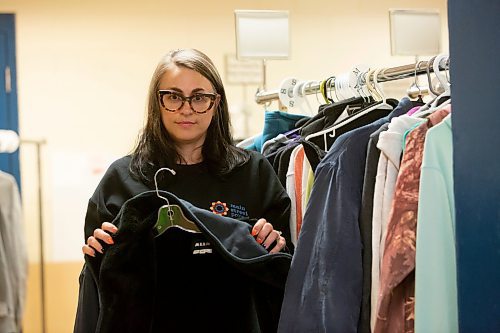 BROOK JONES / WINNIPEG FREE PRESS
Main Street Project Communications Specialist Cindy Titus holding a winter coat as she stands next to a clothing rack at the local shelter's clothing donation area in Winnipeg, Man., Friday, Oct. 20, 2023. Main Street Project is collecting donations of socks for its Socktober campaign. The shelter also needs donations of everyday clothing items and with cooler weather approaching, donations of thermal wear, winter boots, winter jackets, snow pants, scarves and hand warmers are also in need.