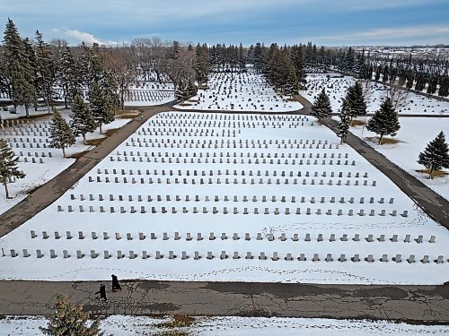 Pedestrians walk through the snow-covered Brandon Municipal Cemetery on Monday after snow fell over the weekend. (Tim Smith/The Brandon Sun)