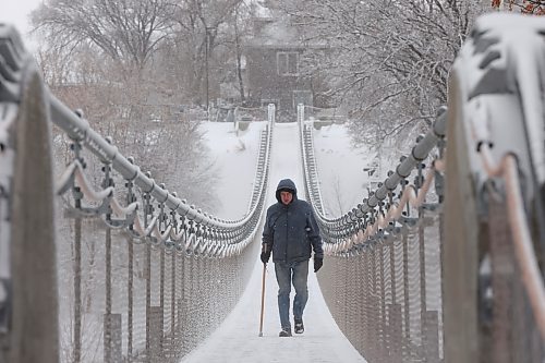 A bundled-up man walks across the snow- and ice-covered Souris Swinging Bridge during flurries on Wednesday afternoon. (Tim Smith/The Brandon Sun)