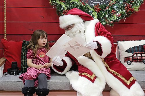 Sophie DeSchutter, 5, of Brandon shows Santa Claus the drawings she made him while visiting him at the Brandon Shoppers Mall on Friday evening. Santa made his first appearance at the mall on Friday and will be there daily until Dec. 23. DeSchutter was the first person in line to meet him. (Tim Smith/The Brandon Sun)