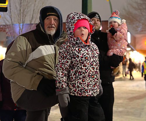 Arabella Quesnel looks on in wonder, as Santa's sleigh comes closer to where she and her family were standing during the Brandon Santa Parade Saturday evening. Abigail Quesnel pauses with her lolipop, to have a look too. (Photos by Michele McDougall/The Brandon Sun) 