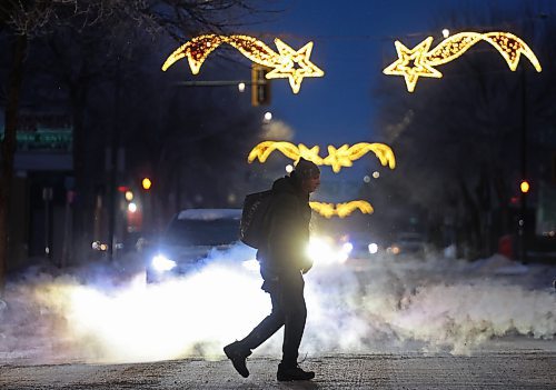 A pedestrian makes their way across Princess Avenue in downtown Brandon at dusk as the Christmas lights above the avenue glow on Tuesday. (Tim Smith/The Brandon Sun)