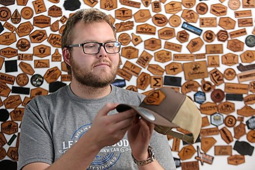 Leatherwood Custom Workwear owner Morgan James inspects one of his company's products in front of his leather logo wall on Monday. James says the ongoing Canada Post strike has caused considerable trouble for his Brandon-based company, as nearly all of his business is conducted through the mail. (Matt Goerzen/The Brandon Sun)