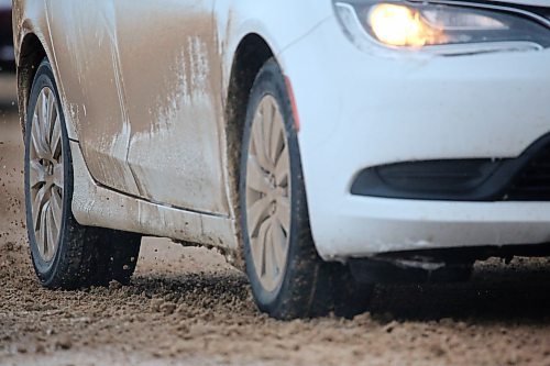 A car travels through snow and sand on First Street on Monday afternoon. (Matt Goerzen/The Brandon Sun)