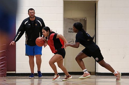 Genesis Lopez Mejia dribbles while Rebecca Alebiosu defends and coach Adam Hartman looks on during Crocus Plainsmen basketball practice on Tuesday. The Grade 11 guard is entering her second season with the varsity girls, kicking off with their Early Bird home tournament today. (Thomas Friesen/The Brandon Sun)