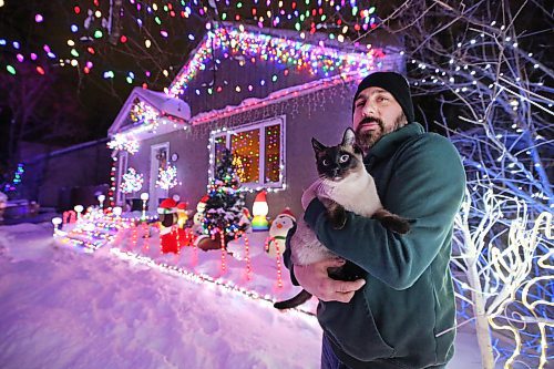 Brandon resident Patrick Stewart holds his family cat Avi, a seven-month-old Siamese feline, outside their brightly-lit home at 522 22nd Street on Monday evening. Stewart and his family have worked since November to set up all the lights used in the holiday display, as a means to raise funds for One At A Time Rescue, a Brandon-based organization that focuses primarily on orphaned animals. (Matt Goerzen/The Brandon Sun)