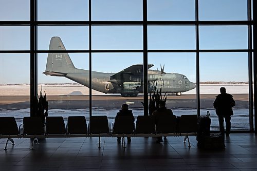 Travellers at the Brandon Municipal Airport look out on a Canadian Forces C-130 Hercules aircraft on the tarmac during a military exercise at the airport on Wednesday. (Tim Smith/The Brandon Sun)