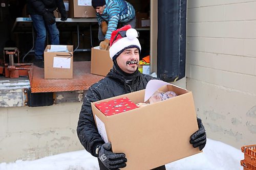 17122024
Gage Wood with Brandon Fire &amp; Emergency Services helps load Christmas hampers into waiting vehicles outside Brandon-Westman Christmas Cheer on 7th Street in Brandon on Wednesday. Volunteers worked all day and evening Wednesday to prep and send out Christmas hampers to families in need for the holidays. Volunteers will be back at it today to deliver the remainder of the hampers.
(Tim Smith/The Brandon Sun)