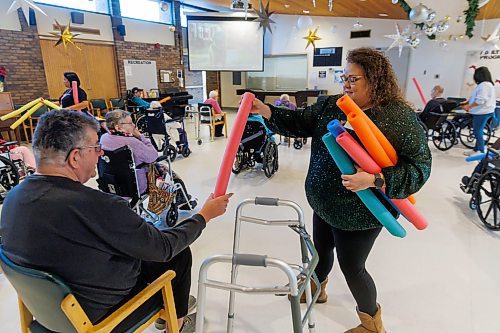 MIKE DEAL / FREE PRESS
Activity worker, Jenna Corby, hands out pool noodles to residents participating in &#x201c;noodle hockey&#x201d; a popular recreation activity at Fred Douglas Lodge (1275 Burrows Ave). 

Reporter: Maggie Macintosh
241219 - Thursday, December 19, 2024.