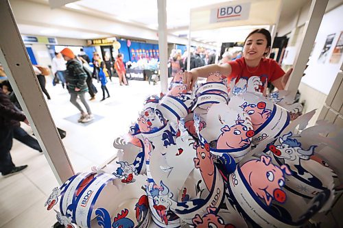 Royal Manitoba Winter Fair volunteer Alisha Ducharme stacks dozens of paper hats especially made for the fair by BDO outside the entrance to the Westoba Place Arena on Monday afternoon. (Matt Goerzen/The Brandon Sun)