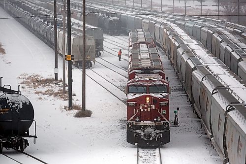 A worker with Canadian Pacific Railway checks a line of train cars during bone-chilling temperatures, windy conditions and minor snow storm on Wednesday afternoon. (Matt Goerzen/The Brandon Sun)
