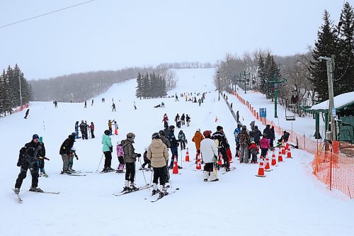 Ski and snowboard enthusiasts line up to board the chair lift at Holiday Mountain. (Matt Packwood/The Brandon Sun)