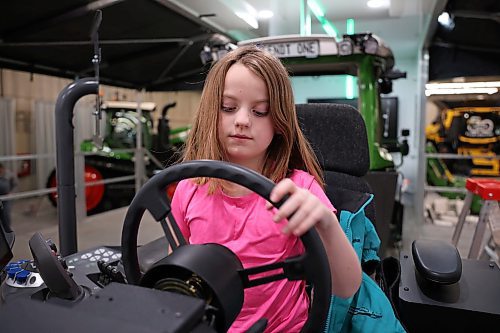 20012025
Eight-year-old Hazel Raupers sits at a Fendt simulator set up for sprayer simulation while her dad Martin Raupers, Field After-Sales Manager for AGCO, sets up their booth and displays with other employees ahead of Manitoba Ag Days at the Keystone Centre in Brandon on Monday. Ag Days kicks off today and runs until Thursday. 
(Tim Smith/The Brandon Sun)