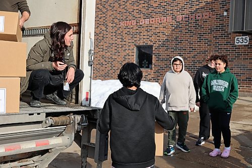 Left: Harvest Manitoba community program director Mika Peterson hands a Meal2Go kit box to King George School students before the formal presentation of the meal boxes to the school Thursday afternoon. (Abiola Odutola/The Brandon Sun)