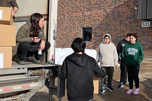 Left: Harvest Manitoba community program director Mika Peterson hands a Meal2Go kit box to King George School students before the formal presentation of the meal boxes to the school Thursday afternoon. (Abiola Odutola/The Brandon Sun)